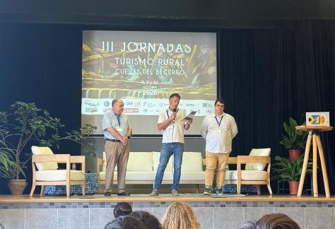 Cuevas del Becerro reivindica el presente de los pueblos en sus III Jornadas de Turismo Rural Tres participantes en el escenario de las III Jornadas de Turismo Rural de Cuevas del Becerro, uno de ellos interviniendo ante el público.